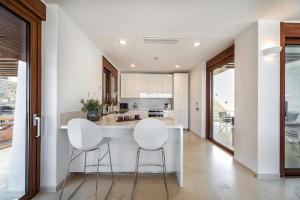 a kitchen with two white stools at a white counter at Elounda Lavender Villa in Elounda