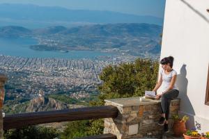 a woman sitting on a ledge reading a book at Archontiko Melanthi in Makrinítsa