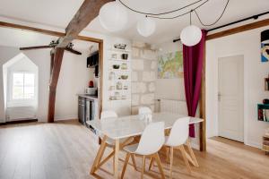 a dining room with a white table and white chairs at Le Grand Mirebeau - Parking privé in Bourges