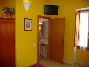 baño amarillo con lavabo y TV en la pared en Aldebaran Centro Storico, en Cagliari