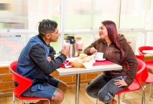 un hombre y una mujer sentados en una mesa comiendo comida en Hostal D' Rosas, en Tacna