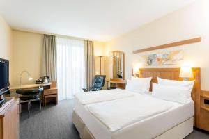 a hotel room with a large bed and a desk at NH Hamburg Horner Rennbahn in Hamburg