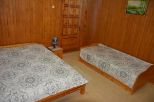two beds in a room with wooden walls at Sadyba Karpatiya in Yaremche