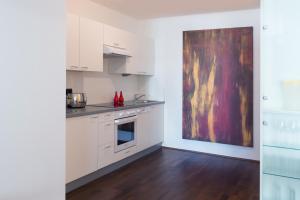 eine Küche mit weißen Schränken und einem Wandgemälde in der Unterkunft Salzburg City Appartement in Salzburg