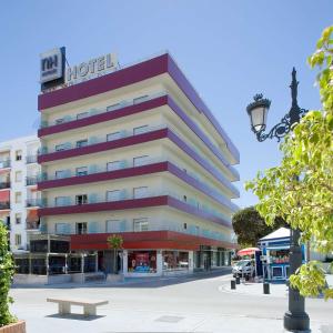 un edificio de hotel con un banco delante en NH San Pedro, en Marbella
