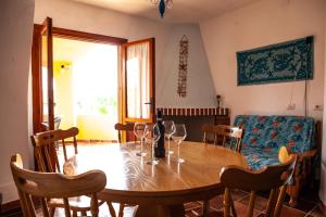 uma sala de jantar com uma mesa de madeira e copos de vinho em Casa vacanze a 200 mt dalla spiaggia di Ottiolu - fpo1 e fp02 em Porto Ottiolu