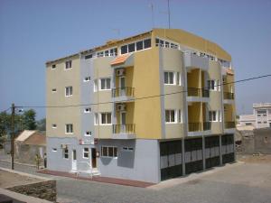um edifício amarelo e branco ao lado de uma rua em Residencial Pôr do Sol em Porto Novo