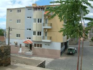 um edifício alto com um veículo verde estacionado ao lado em Residencial Pôr do Sol em Porto Novo