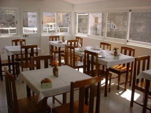um restaurante com mesas, cadeiras e janelas brancas em Residencial Pôr do Sol em Porto Novo