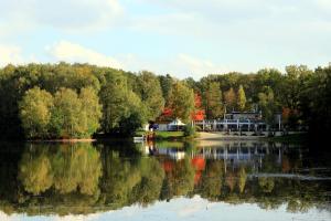 Blick auf einen See mit einem Haus im Hintergrund in der Unterkunft Hotel am Springhorstsee in Großburgwedel