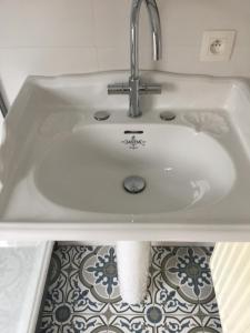 a white sink in a bathroom with a tile floor at Jules en ville 1 in Bastogne