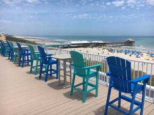 een rij blauwe stoelen en een tafel op een terras met een strand bij Chateau by the Sea in Cocoa Beach