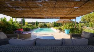 a patio with a swimming pool and a wooden umbrella at Villa d Agathe en Provence Graveson in Graveson