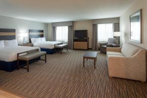 um quarto de hotel com duas camas, um sofá e uma televisão em GrandStay Hotel & Suites em Cannon Falls