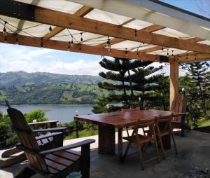 a wooden table and chairs on a patio with a view of a lake at Villa La Loma in Concepción de La Vega