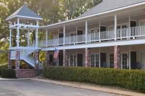 uma grande casa branca com um alpendre e uma bandeira americana em The Lodge at The Bluffs em Saint Francisville