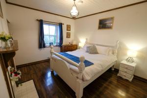 a bedroom with a white bed and a window at The Cottage Hillside in Westport