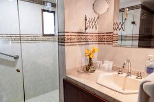 
a bathroom with a sink, mirror, and bath tub at Hotel Casa Laureles in Medellín
