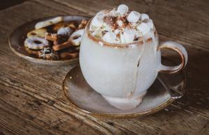 een kopje koffie op een tafel met een bord koekjes bij Hotel Alpenblick Zillertal in Hippach