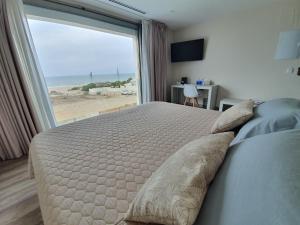 Hotel Boutique Aroma de Mar في شيكلانا دي لا فرونتيرا: غرفة نوم بسرير مع اطلالة على الشاطئ