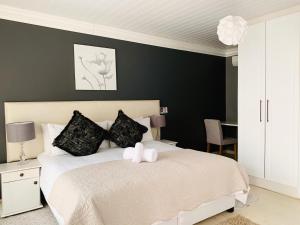 a bedroom with a white bed with a black wall at Resthaven Guest House in Mthatha