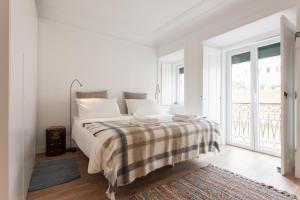 una camera bianca con un letto con una coperta a quadri di FLH Santa Marta Portuguese Flat a Lisbona
