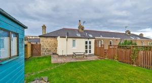 a house with a backyard with a bench in the yard at Cosy Cottage Close to East Beach, Shops, Restaurants and RAF base in Lossiemouth