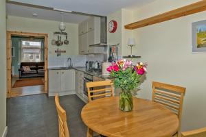 a kitchen with a table with a vase of flowers on it at Cosy Cottage Close to East Beach, Shops, Restaurants and RAF base in Lossiemouth