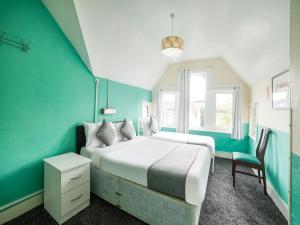 1 Schlafzimmer mit 2 Betten und einer grünen Wand in der Unterkunft OYO Devine Beach Hotel, Westcliff Southend-On-Sea in Southend-on-Sea