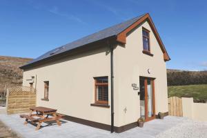 a small white cottage with a picnic table in front of it at Dolmen Cottage in Glencolumbkille