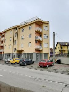 a building with cars parked in a parking lot at Apartman Jelacic Vinkovci in Vinkovci