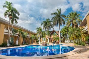 a pool at a resort with palm trees at Tecnohotel Mérida Norte in Mérida