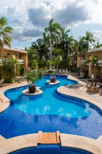 una piscina en un complejo con agua azul y palmeras en Tecnohotel Mérida Norte en Mérida
