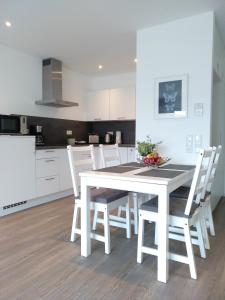 uma cozinha branca com uma mesa e cadeiras brancas em Boland Apartments em Rust