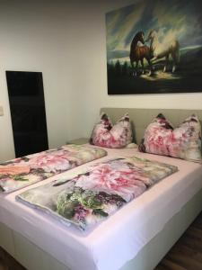 a bed with floral sheets and a painting on the wall at Apartment Elfi in Leibnitz