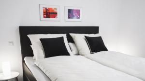 2 Betten mit schwarzen und weißen Kissen in einem Zimmer in der Unterkunft Boland Apartments in Rust
