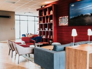 eine Lobby mit einem Sofa und Stühlen sowie einem TV in der Unterkunft Ibis Rouen Centre Rive Gauche Mermoz in Rouen