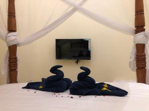 twee zwanen handdoeken op een bed met een tv bij Bottoms Up in Zanzibar City