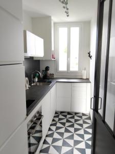 a kitchen with white cabinets and a black and white checkered floor at Appartement au centre de Saint Briac in Saint-Briac-sur-Mer
