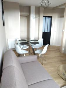 sala de estar con sofá, mesas y sillas en Appartement au centre de Saint Briac, en Saint-Briac-sur-Mer