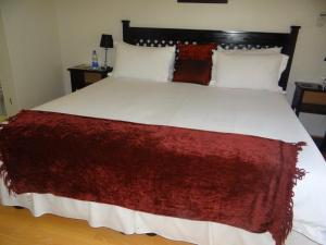 Una gran cama blanca con una manta roja. en Lilliz Guest House, en Mthatha