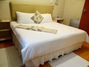姆塔塔的住宿－Lilliz Guest House，一张大白色的床,位于带两张桌子的房间