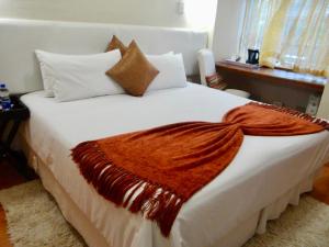 una camera da letto con un letto bianco e una coperta arancione di Lilliz Guest House a Mthatha