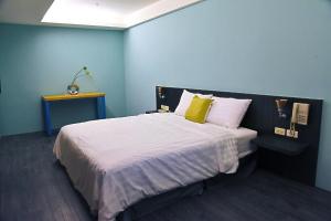 1 dormitorio azul con 1 cama grande con almohadas amarillas en Tian Fang Ye Tan Hotel, en Yilan City