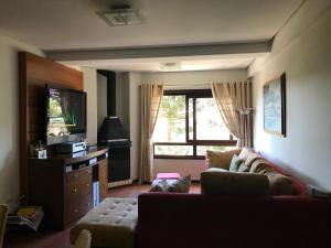 sala de estar con sofá y TV de pantalla plana en Apartamento Orsi, en Gramado