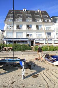 サン・ピエール・キブロンにあるHôtel De La Plageの海岸船を持つホテル前に立つ男