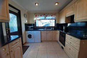 a large kitchen with a washer and dryer in it at Leafield Holiday Home in Stranraer