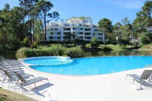 a swimming pool with chairs and a building in the background at Green Park Apartamento con Balcón vista Lago in Punta del Este