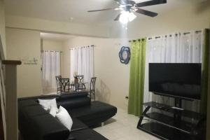 a living room with a black couch and a ceiling fan at Gorgeous hideout, close to tourist attractions in Jamaica in Belle Air Summit