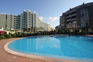 a large swimming pool in a city with tall buildings at Menada Sunny Beach Plaza Apartments in Sunny Beach